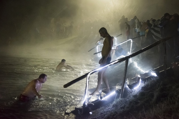 Image: Russian Orthodox believers bathe in ice water in a pond to mark Epiphany