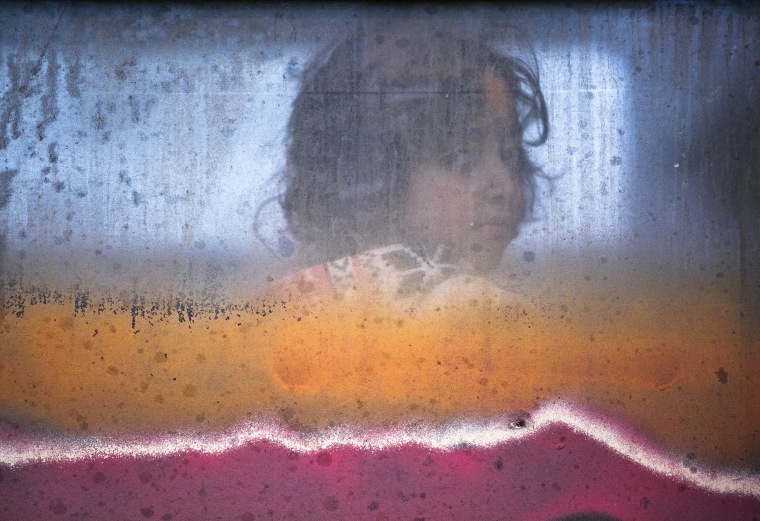 Image: A migrant child looks out of a window of a passenger train in Presevo