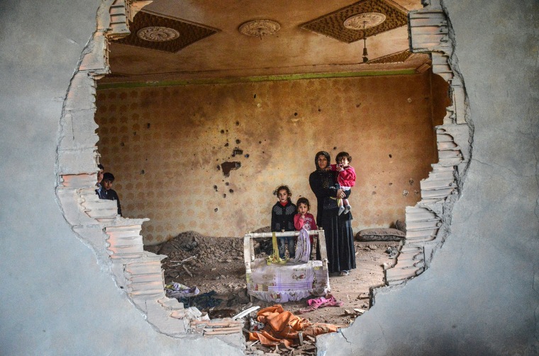Image: A women and her children stand in the ruins of battle-damaged house in the Kurdish town of Silopi