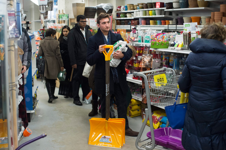 Image: A customer waits in a line to purchase shovels and ice melt
