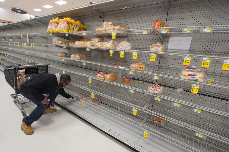 Image: A customer looks at the heavily depleted bread section of a grocery store