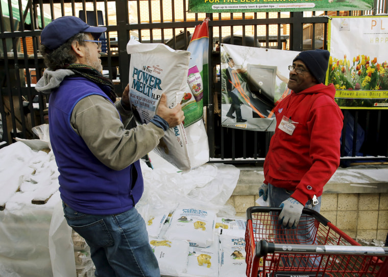 Image: An employee watches a customer carry out a bag of ice melt