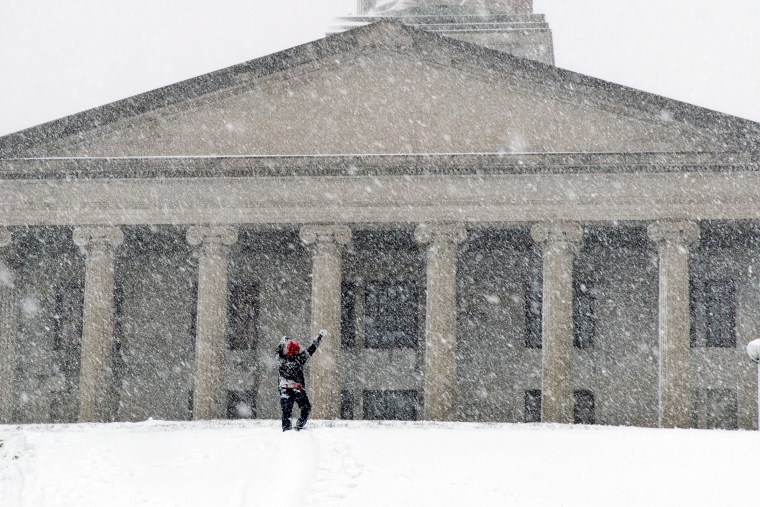 Image: A man celebrates making it up a steep, snow-covered hill in Nashville