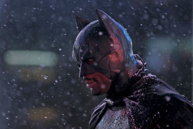 Image: A man dressed as \"Batman\" stands as it begins to snow in Times Square in the Manhattan borough of New York