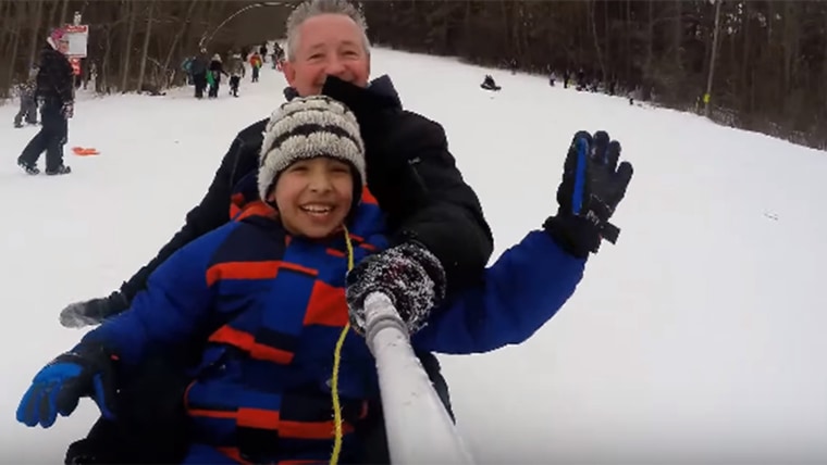 Ontario policeman David McNab has fun sliding down a hill in Peterborough, Ontario, with one of three Syrian refugee children that he and a group of local citizens are helping acclimate to life in Canada.