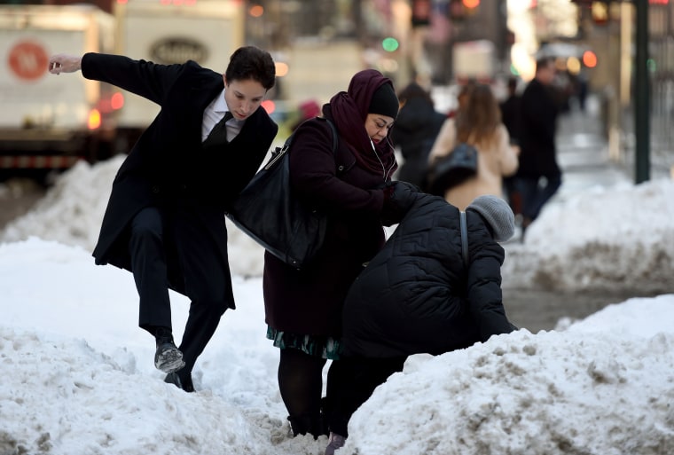 Image: People try to navigate a snowbank in the middle of Park Avenue
