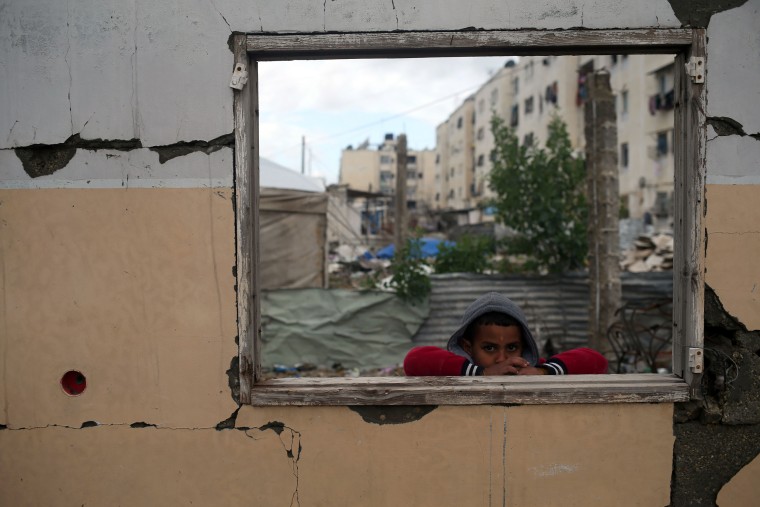 Image: A Palestinian boy looks on from the window of a building