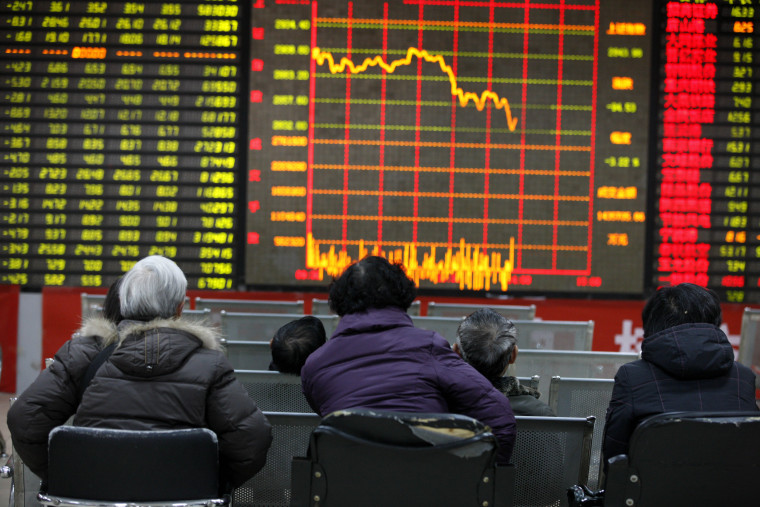 Image: Concerned Chinese investors look at a stock index and prices of shares at a stock brokerage house