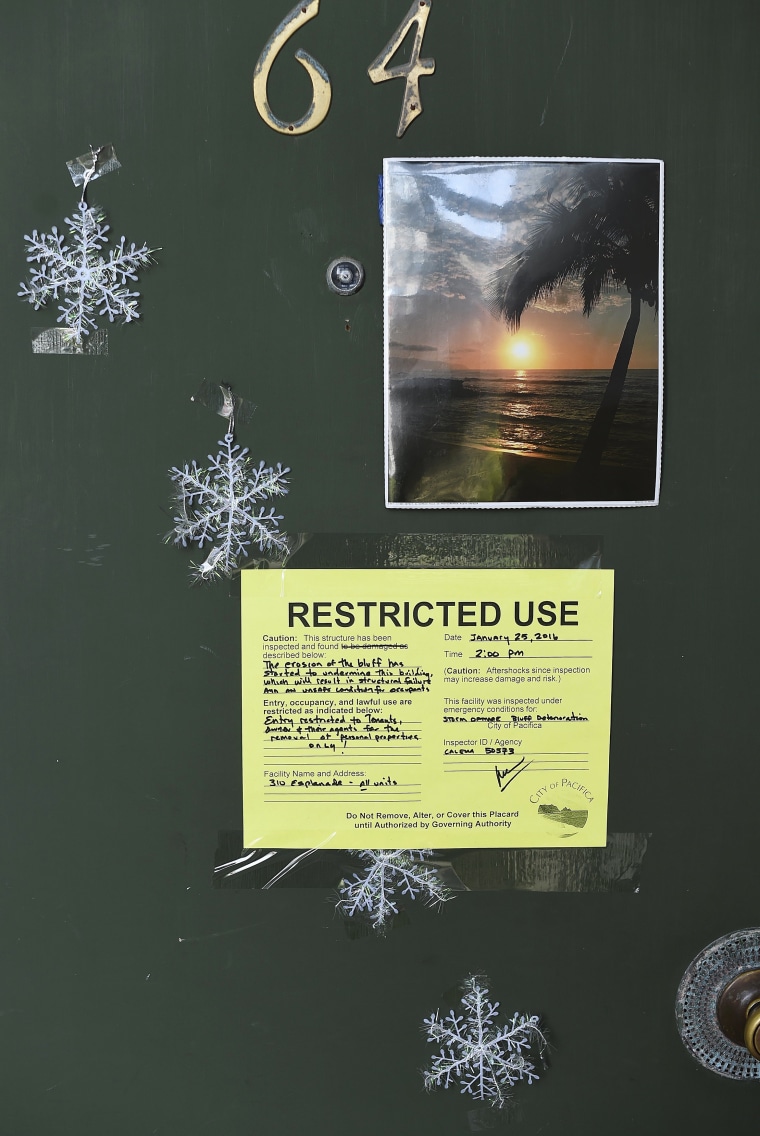 Image: A warning notice is pictured on a door at an uninhabitable apartment, in danger of collapsing due to storm erosion, in Pacifica