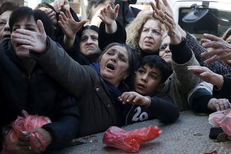 Image: People reach out to receive free produce handed out by farmers in Athens, Greece