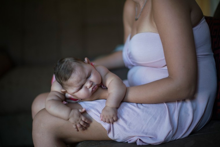 Image: Gleyse Kelly da Silva holds her daughter Maria Giovanna as she sleeps in their house in Recife