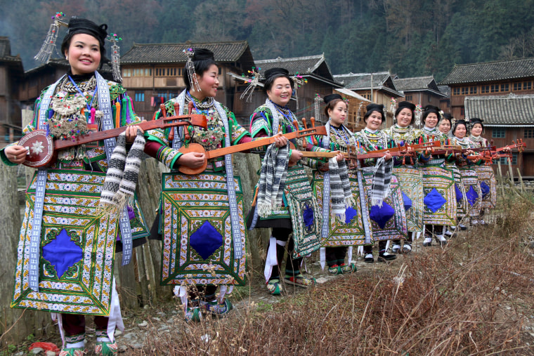 Image: Ethnic Dong women wearing traditional costumes, hold \"pipas\", a traditional instrument