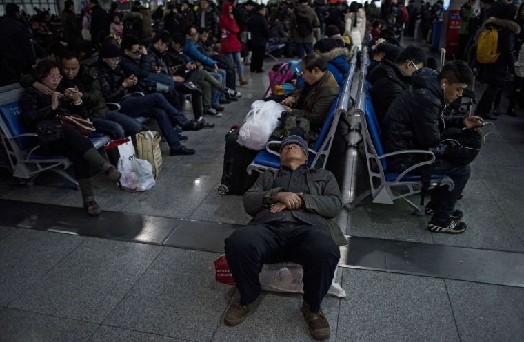 Image: Passengers wait to board their trains as they head to their hometowns