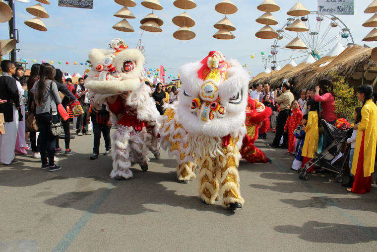 Vietnamese lion dancers make their way under the cultural village's back gate.