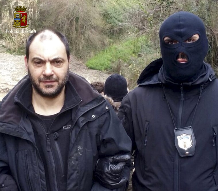 Image: A police officer escorts fugitive Giuseppe Ferraro