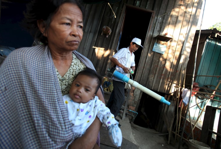 Image: A woman carries her grandson as a health official collects mosquitos and larva at her home to check for Zika virus at a village in Phnom Penh, Cambodia