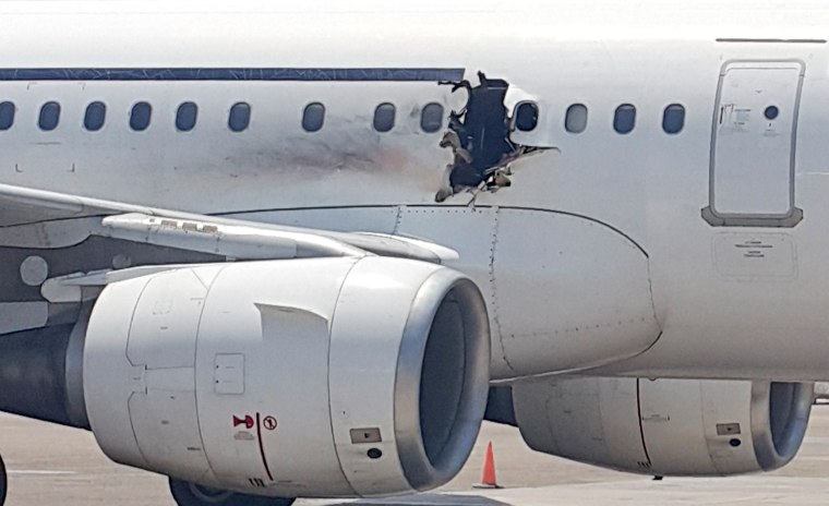 Image: A hole is seen in a plane operated by Daallo Airlines as it sits on the runway of the airport