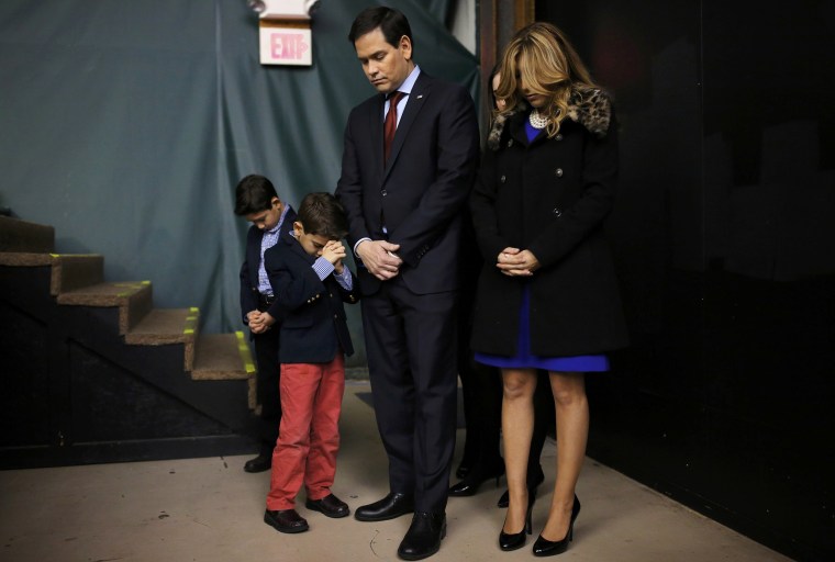 Image: Republican U.S. presidential candidate Marco Rubio prays with his family as they attend the Republican caucus at the 7 Flags Event Center in Clive