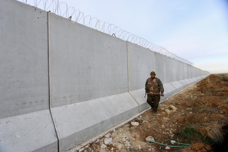 Image: A Kurdish People's Protection Units (YPG) fighter walks near a wall