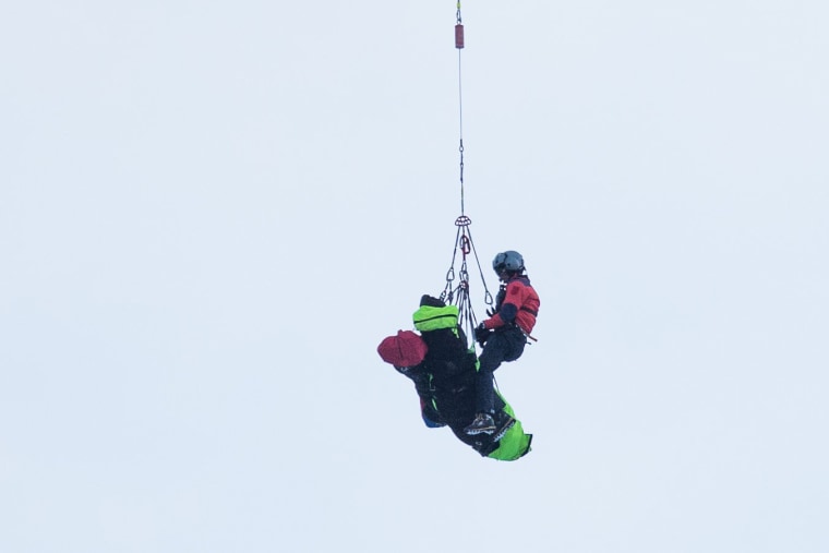 Image: Rescue teams airlift the bodies by helicopter of a group of people buried by an avalanche