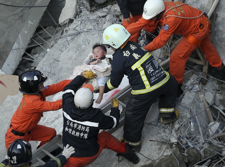 Image: Rescue personnel help a child rescued at the site where a 17-storey apartment building collapsed during an earthquake in Tainan