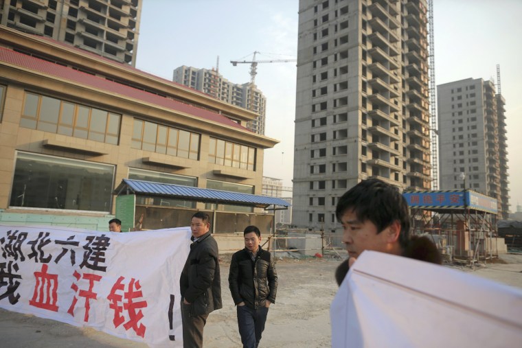 Image: Migrant workers display banners at the construction site of Zixia Garden development complex in Qianan, Tangshan City