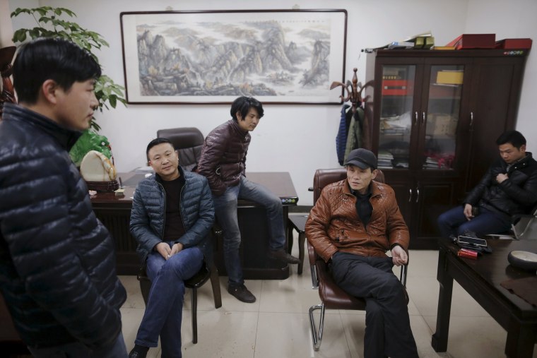 Image: Migrant workers pass time at the offices of a subcontractor company at the construction site of Zixia Garden development complex in Qianan, Tangshan City