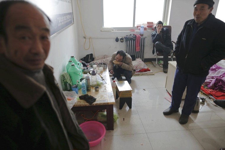 Image: Migrant workers eat breakfast and smoke after waking up at the offices of a subcontractor company at the construction site of Zixia Garden development complex in Qianan, Tangshan City