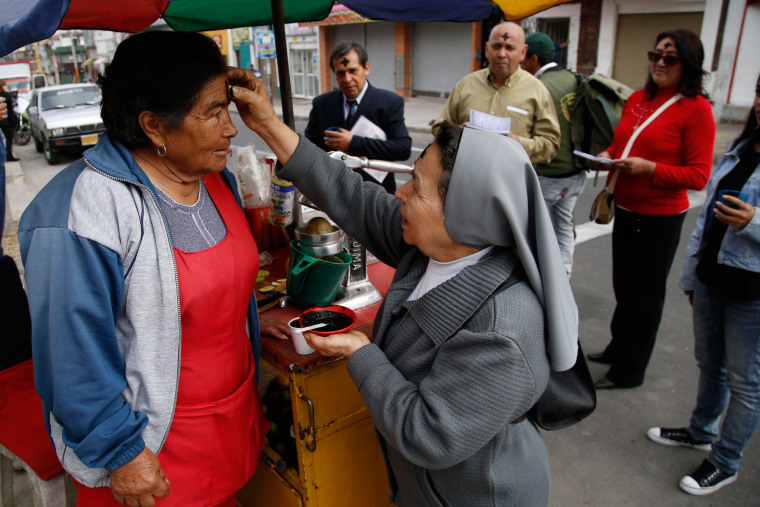 Image: A Catholic nun places ashes in the shape of a cross on a street vendor's forehead