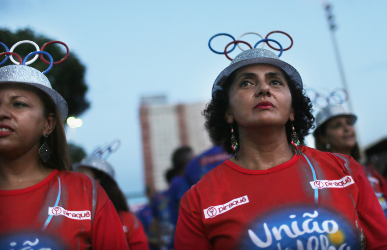 Image: Women with the Uniao da Ilha do Governador samba school wear Olympic ring hats during a pre-Carnival rehearsal