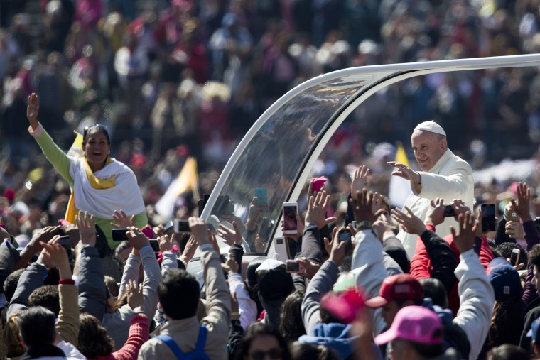 Image: Pope Francis waves to the crowd, aboard the popemobile in Mexico City's main square