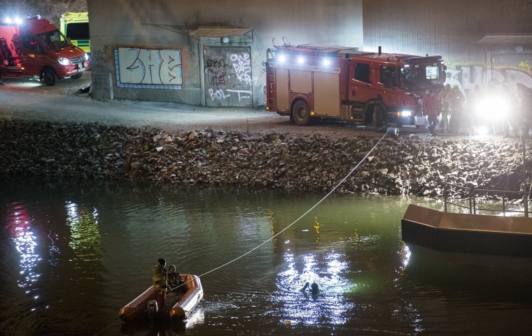 Image:  Divers and rescuers search for the victims of a deadly car crash in the canal under the E4 highway bridge in Sodertalje