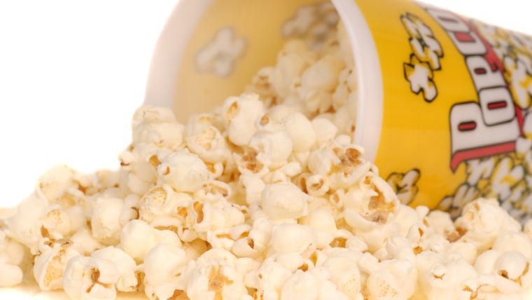 Container of delicious movie popcorn with popcorn spilling out