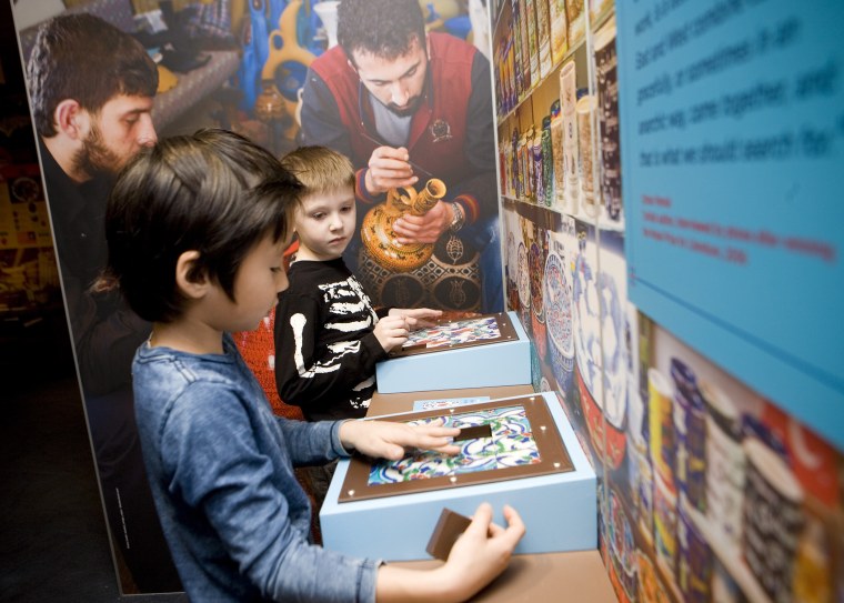 Children feel ceramic tiles at a stall in the global marketplace at the Children’s Museum of Manhattan’s new exhibit, “America to Zanzibar: Muslim Cultures Near and Far.”