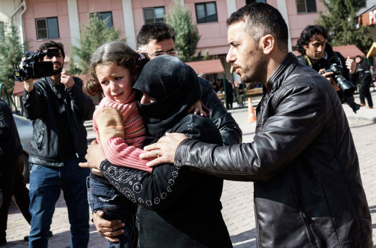 Image: A Turkish man helps a Syrian woman carrying a wounded Syrian girl to a hospital in Kilis, Turkey after airstrikes in Northern Syria