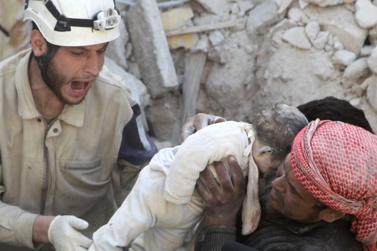 Image: A man holds the body of a dead child as a civil defence member reacts after airstrikes by pro-Syrian government forces in the rebel held al-Qaterji neighbourhood of Aleppo,