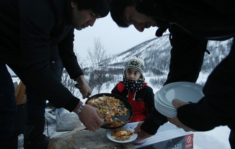 Image: Afghan asylum seeker Roheek Yausofi waits his turn for food cooked on an open fire