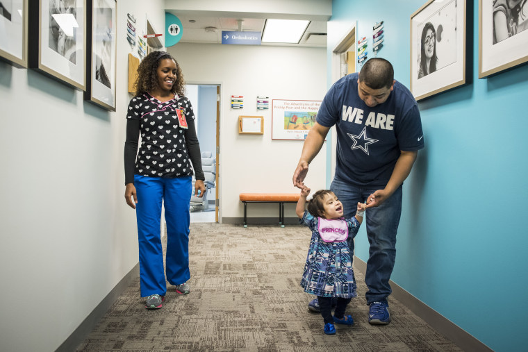 Eric Mata holds daughter Knatalye’s hands as she walks down the hall of a clinic at Texas Children’s Hospital.