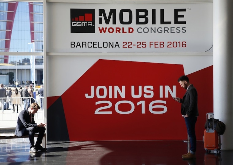 People look at their mobiles in front of the 2016 Mobile World Congress edition banner in Barcelona