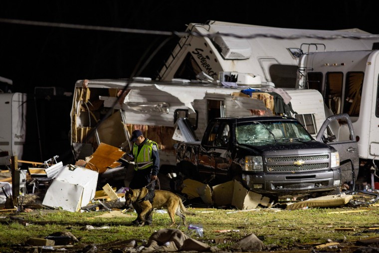 Image: First responders search the remains of trailers and vehicles