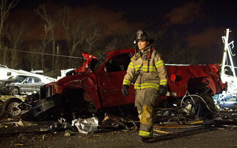 Image: First responders search the remains of trailers and vehicles