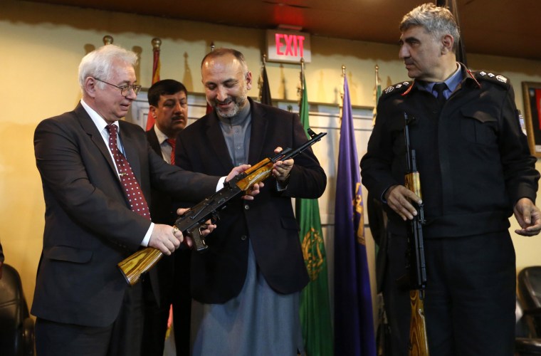 Image: Russia's Ambassador to Kabul Alexander Mantytskiy hands an AK-47 to Afghan National Security Adviser Mohammad Hanif Atmar