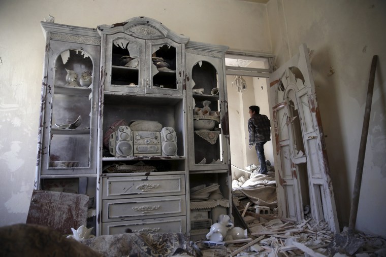 Image: A boy inspects a damaged house in the rebel held besieged city of Douma, a suburb of Damascus