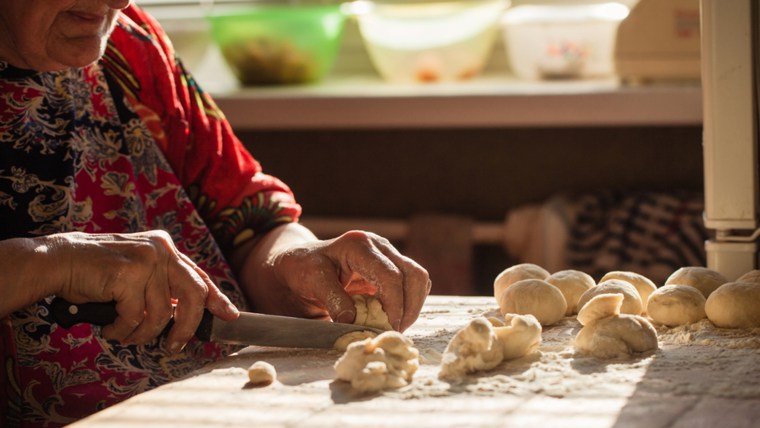 Woman prepares pies on a table in her home kitchen.