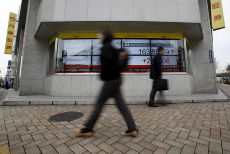 Pedestrians walk pass an electronic board outside a brokerage in Tokyo