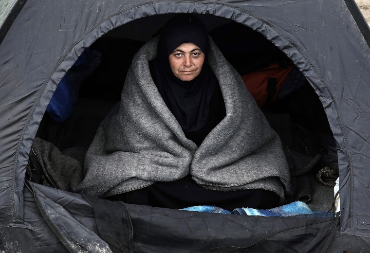 A refugee sits in a tent covered with a blanket during a rainy day in a field outside the refugee camp in Idomeni, northern Greece. At least 10,000 Syrian and Iraqi refugees have been waiting for days at the Idomeni crossing on Greece's border with Macedonia, in an official shelter and in tents that they set up in the fields.