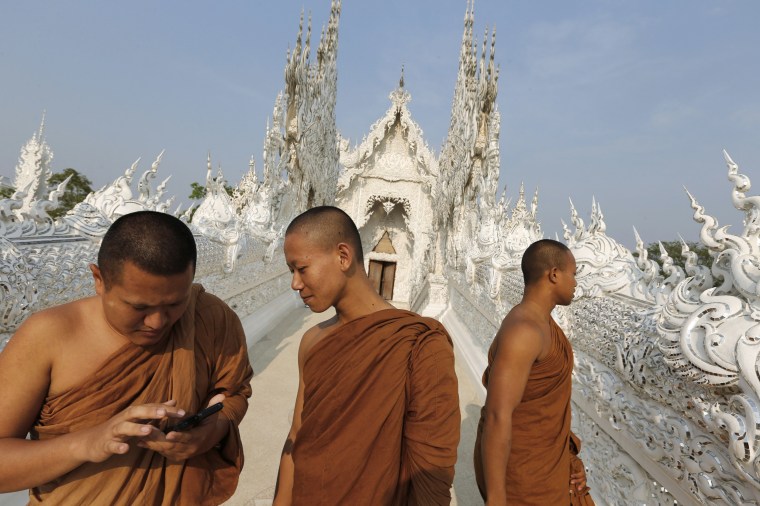 Buddhist monks tour Wat Rong Khun, also know as the White Temple, designed by Thai artist Chalermchai Kositpipat in Chiang Rai Province, Thailand.