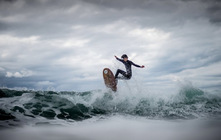 Image: A surfer rides a wave on a day of swells generated by strong winds