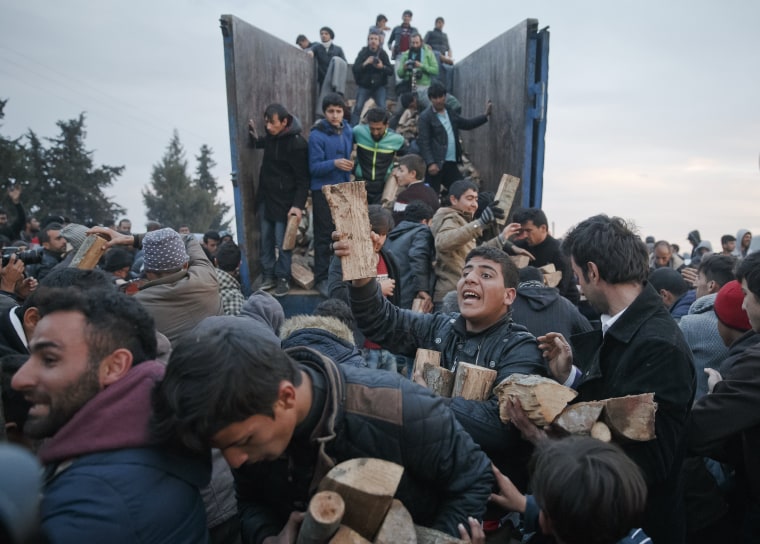 Image: Migrants mob a truck bringing donated firewood at the northern Greek border station of Idomeni