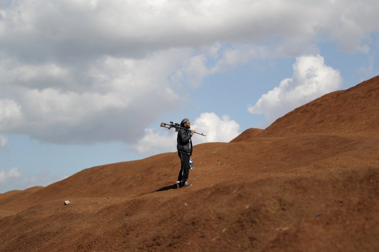 Image: A rebel fighter from 'Jaysh al-Sunna' holds his weapon as he stands behind sand barricade in Tel Mamo village, in the southern countryside of Aleppo